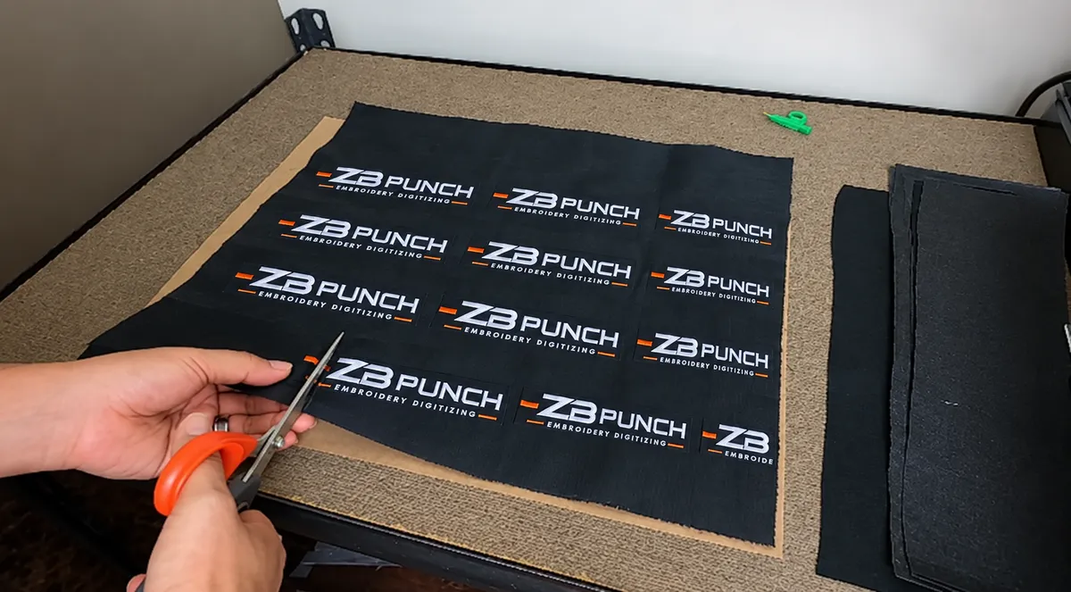 A sheet of embroidered ZB Punch patches being cut out by hand
